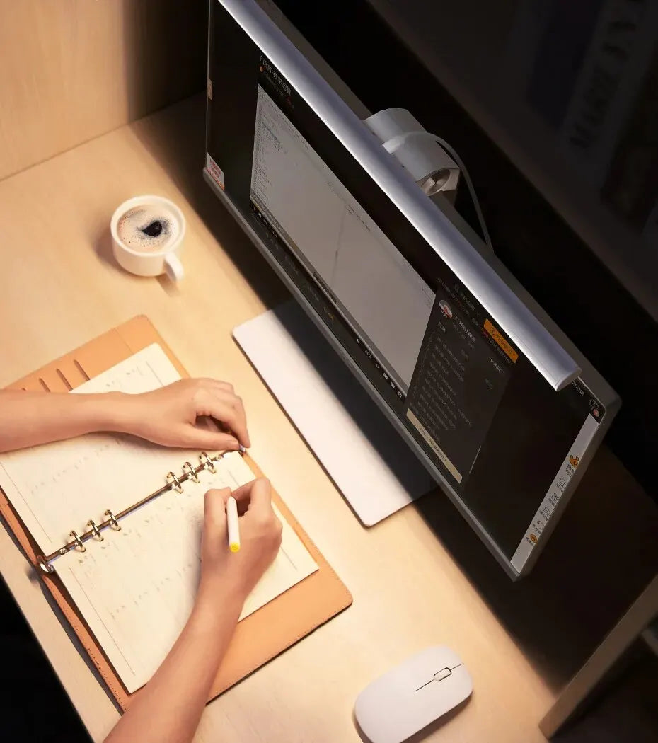 birds eye view of Person working at a computer with a lamp attached to the top of the monitor